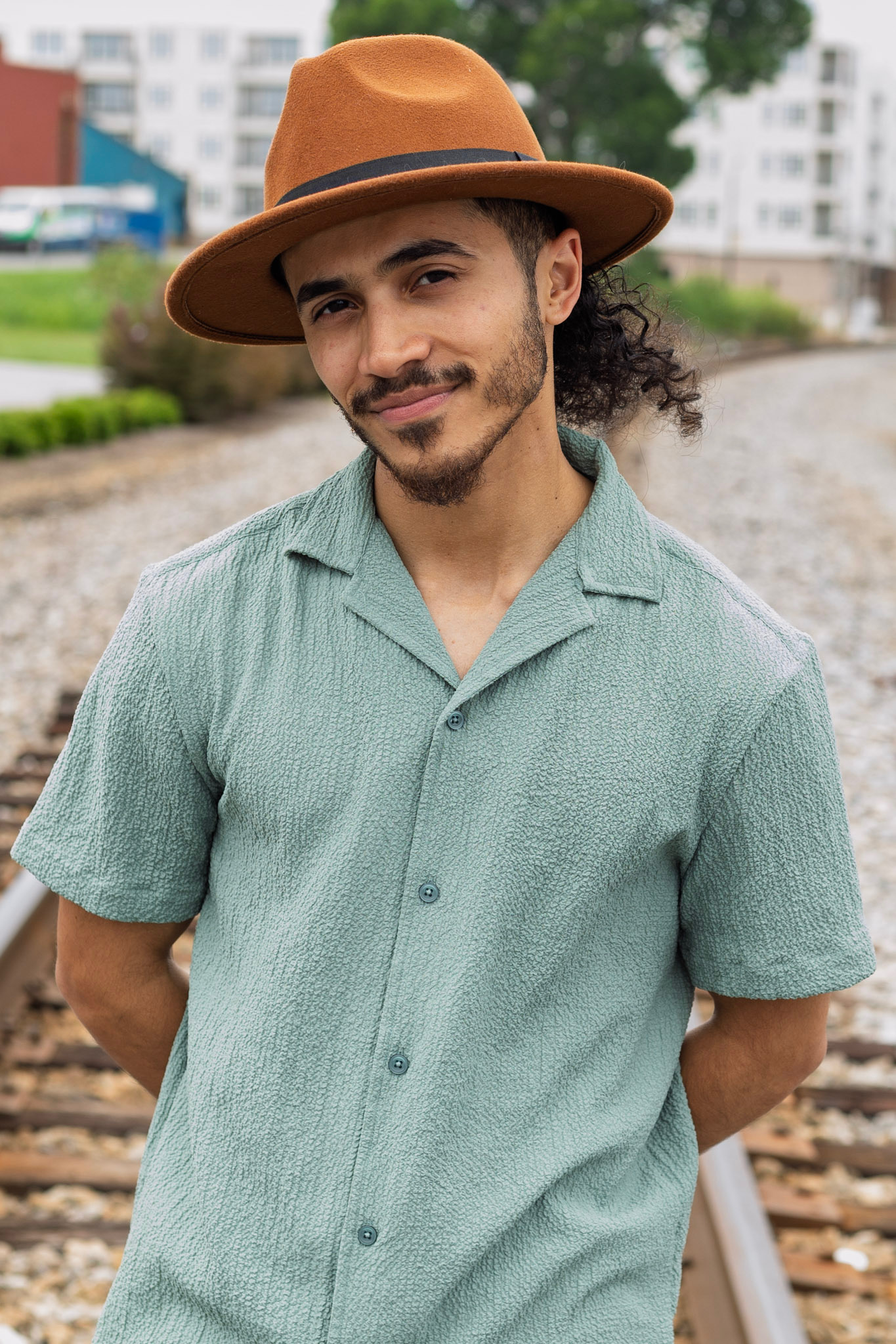 Portrait of Cesar Cruz in a rust fedora and sage shirt